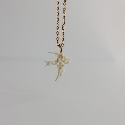 Colar dourado com pendente branco em forma de pássaro