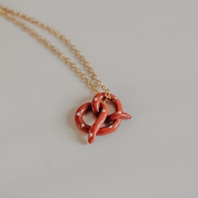 Colar com pendente de cobra vermelha com pintas brancas em fundo cinzento