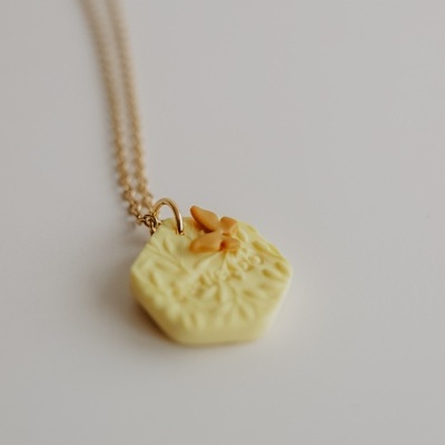Colar com pendente hexagonal amarelo claro com textura floral e flores em relevo