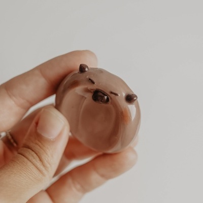 Chocolate em forma de rosto de cachorro com detalhes escuros sendo segurado por uma mão