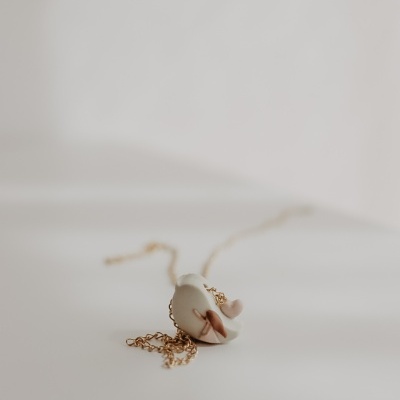 Colar com pendente branco em forma de meia-lua e detalhes em rosa e castanho