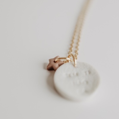 Colar com pingente redondo branco e estrela castanha em fundo branco