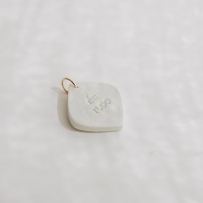 Pingente quadrado branco com texto 'ÉS TUDO' e argola dourada