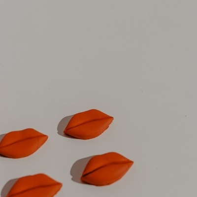 Quatro objetos em forma de lábios laranja sobre fundo branco