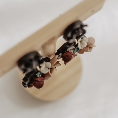 Brincos florais em base preta na banca de madeira