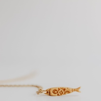 Colar dourado com pendente em forma de peixe com padrão gravado