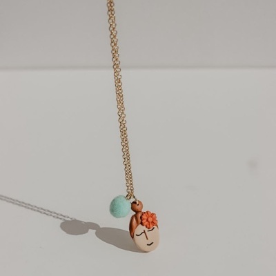 Colar com pendente em forma de rosto estilizado e bola azul pastel