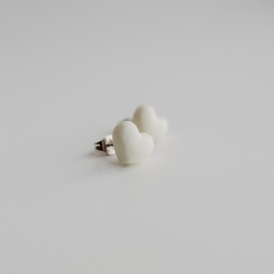 Brincos pequenos em forma de coração branco sobre fundo branco