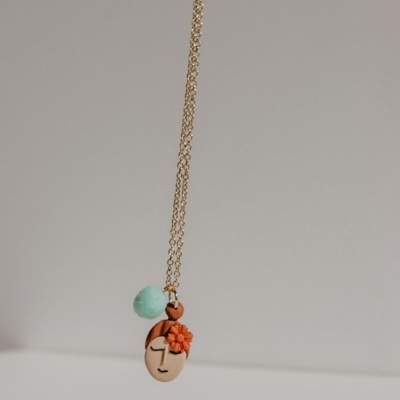 Colar dourado com pendente de rosto estilizado e flor orange