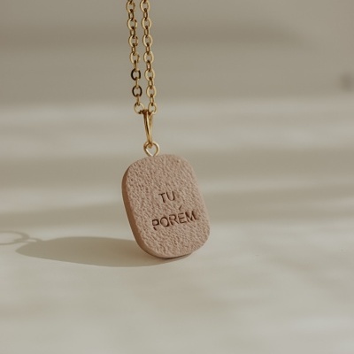 Colar pendente bege texturizado com gravação e corrente dourada