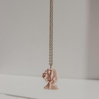 Colar com pendente rosa claro em forma abstrata pendurado em corrente dourada