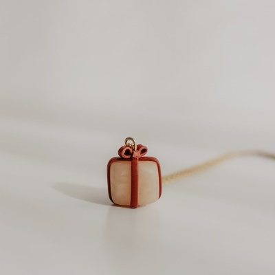 Colar com pendente em forma de presente com laço castanho e corrente dourada