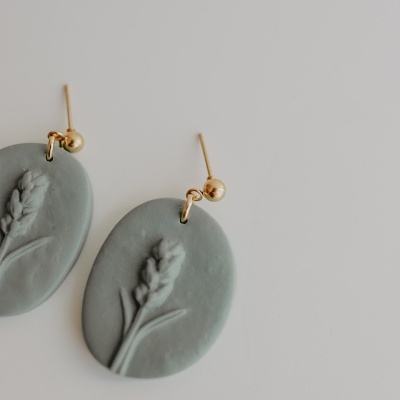 Brincos ovais cinzento azul com relevo e estrutura metálica dourada