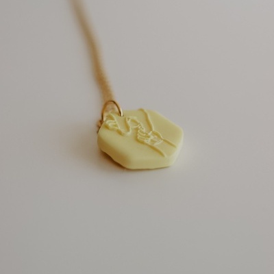 Colar com pendente de resina amarela com relevo e correntinha dourada
