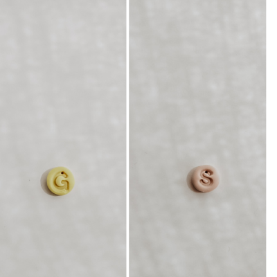 Botões redondos amarelo com G e bege com S sobre fundo claro