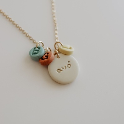 Colar dourado com pendentes redondos coloridos e a palavra 'avó'