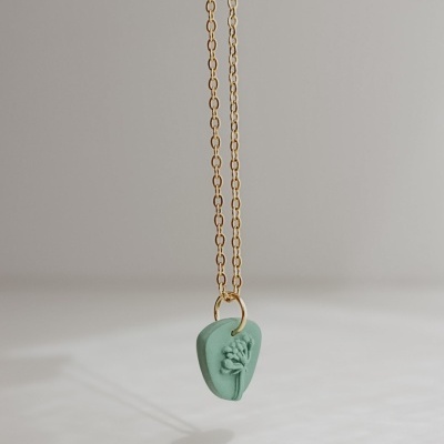 Colar dourado com pendente verde com relevo floral