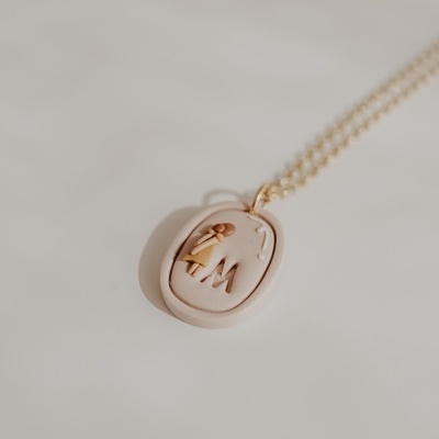 Colar com pendente oval decorado com relevo e corrente dourada