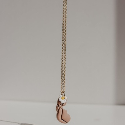 Colar dourado com pendente em forma de coração cor de rosa e flor branca