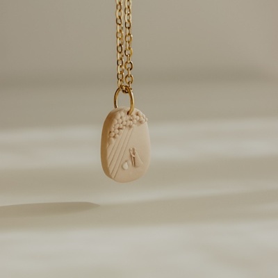 Colar com pingente bege texturizado e corrente dourada