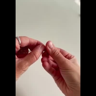 Mãos segurando e manipulando objeto vermelho flexível em fundo claro