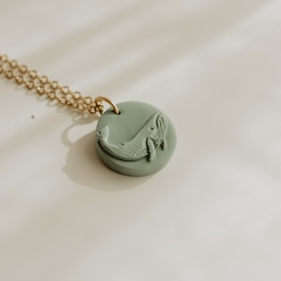 Colar com pendente redondo verde com baleia em relevo e corrente dourada
