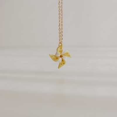 Colar com pendente de moinho de vento bege com manchas douradas