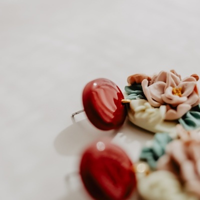 Brincos com base vermelha e flores detalhadas em tons rosa, verde e branco