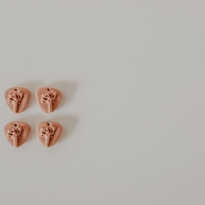 Quatro botões terracota em forma de coração com design floral em branco