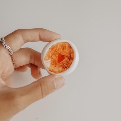 Mão segurando tigela pequena com pintura laranja