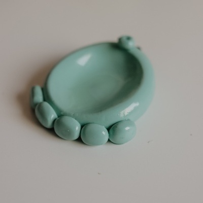 Pequeno prato cerâmico verde-água com elementos ovais na borda