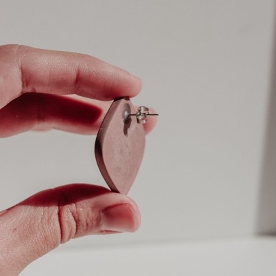 Brinco em forma de coração cor de rosa claro segurado pela mão