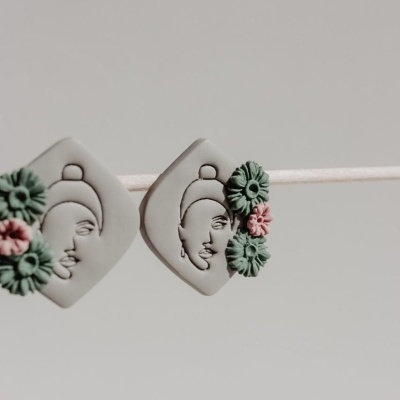 Brincos quadrados cinzentos com relevo e flores verdes e rosa numa corda