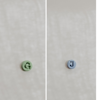 Botões verdes-água e azul com letras G e J em relevo sobre fundo claro