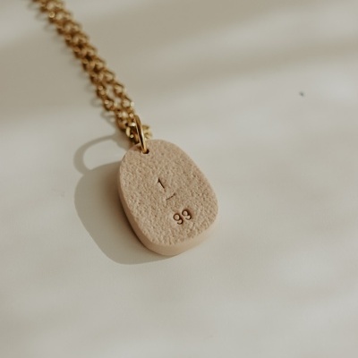 Colar com pendente oval bege claro e corrente dourada