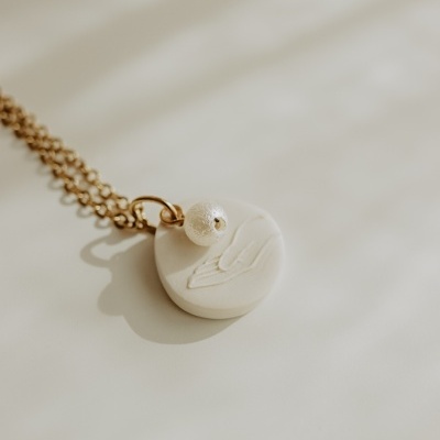 Colar dourado com pendente cerâmico branco e esfera branca texturada