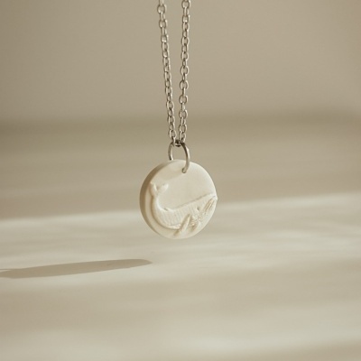 Colar com pendente redondo creme com desenho de baleia em relevo