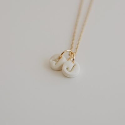 Colar com pedras brancas em corrente dourada sobre fundo branco