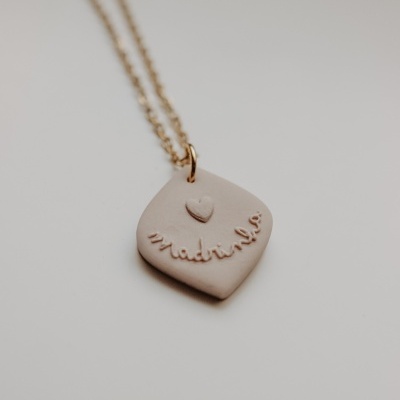 Colar com pendente de cerâmica bege com o texto madrinha e coração em relevo