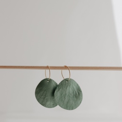 Brincos verdes redondos com argolas douradas pendurados