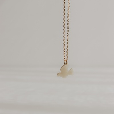 Colar dourado com pendente branco em forma de pomba