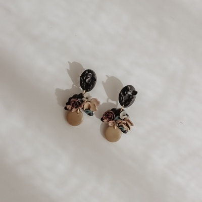 Brincos com base preta oval e flores em tons castanho, bege e azul com círculo bege pendente