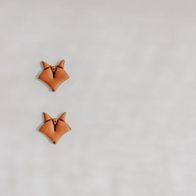 Dois objetos decorativos em forma de raposa castanhos sobre superfície cinza