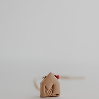 Colar com pendente em forma de casa castanho claro com detalhe de folha