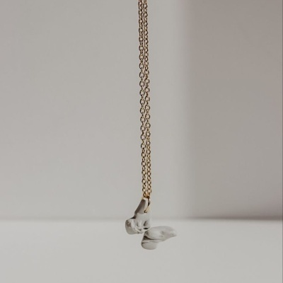 Colar com corrente dourada e pendente branco em forma de pomba