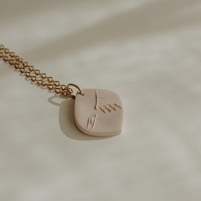 Colar dourado com pendente quadrado bege claro com relevo abstrato