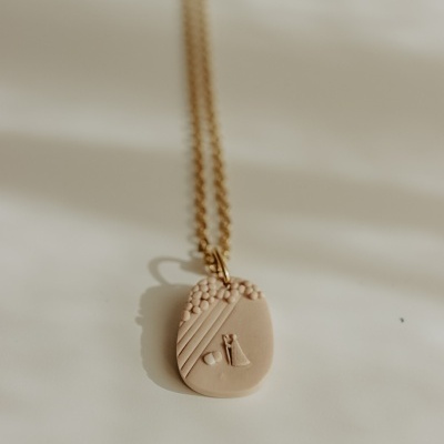 Colar com pendente oval creme texturizado em fundo branco