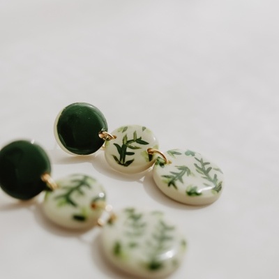 Brincos com círculos verdes e brancos com padrão de folhas