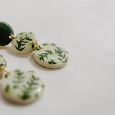 Brincos com círculos decorados com folhas verdes e círculo verde sólido