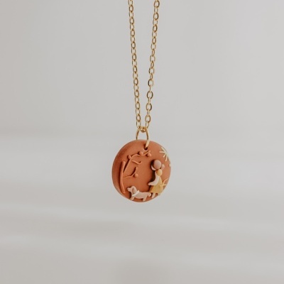 Colar com pendente de relevo castanho e creme com corrente dourada